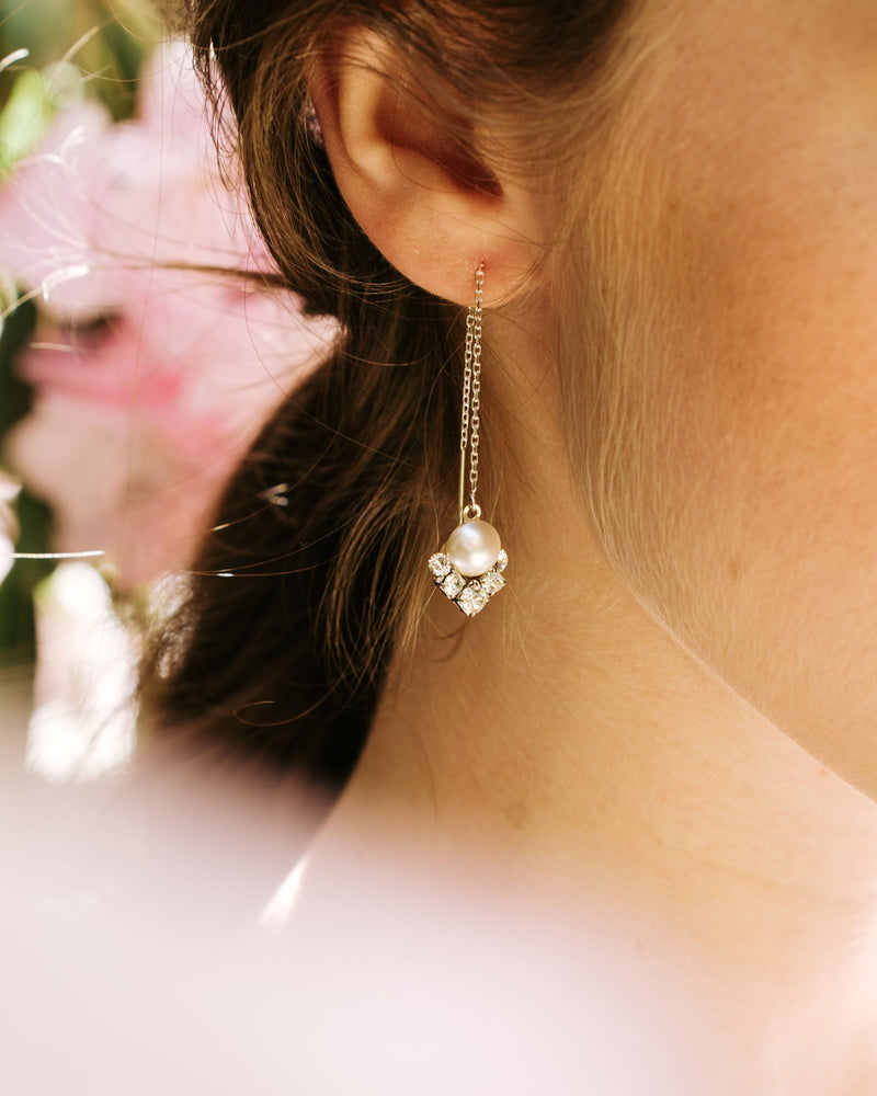 A close on model of the celestial threader drop earring in silver with cream pearl.