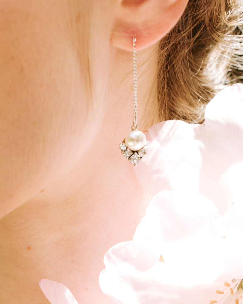 A close on model view of the celestial threader drop earring in silver with cream pearl.
