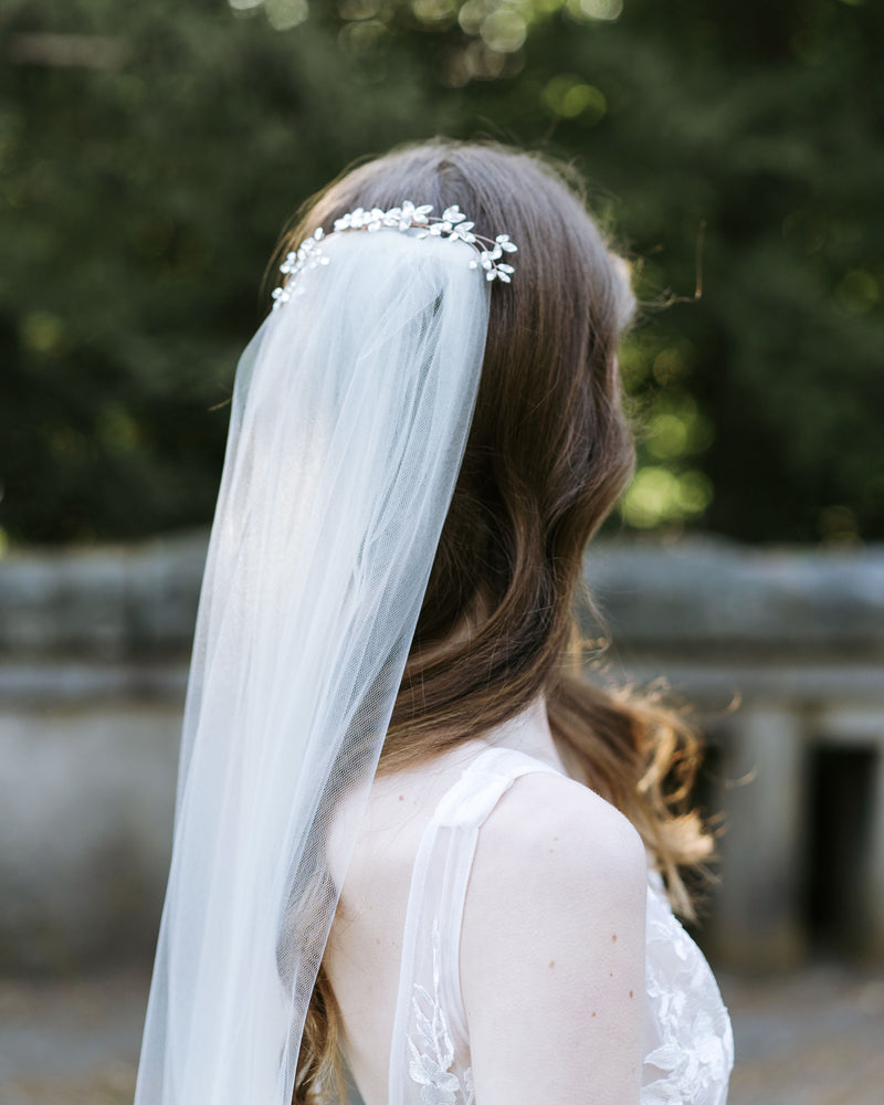 A model with bridal waves in her hair wears a dramatic crystal comb over a tulle veil.