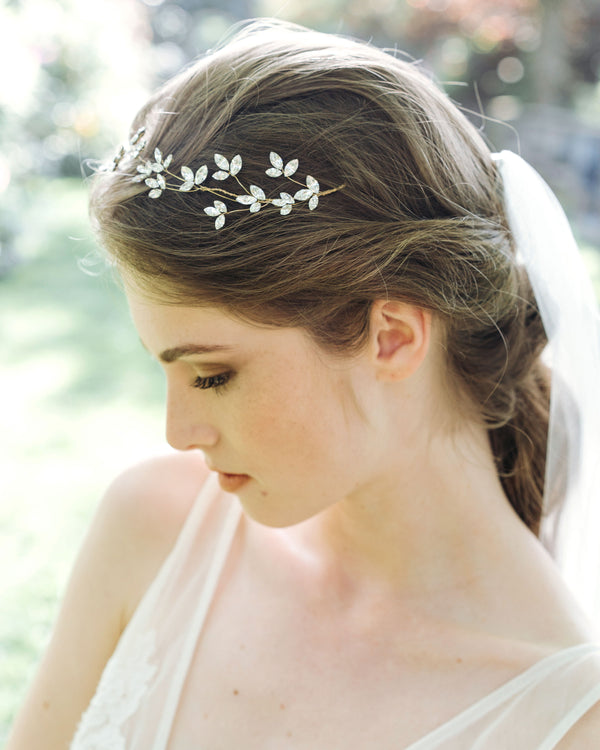 A model wears a floral crystal hair vine with crystal blossoms and a tulle veil.
