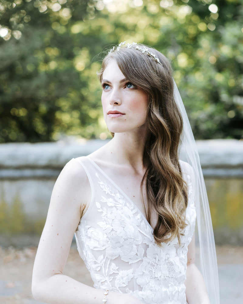 A model poses at Stanley Park, wearing a crystal blossom hair vine in soft bridal waves.