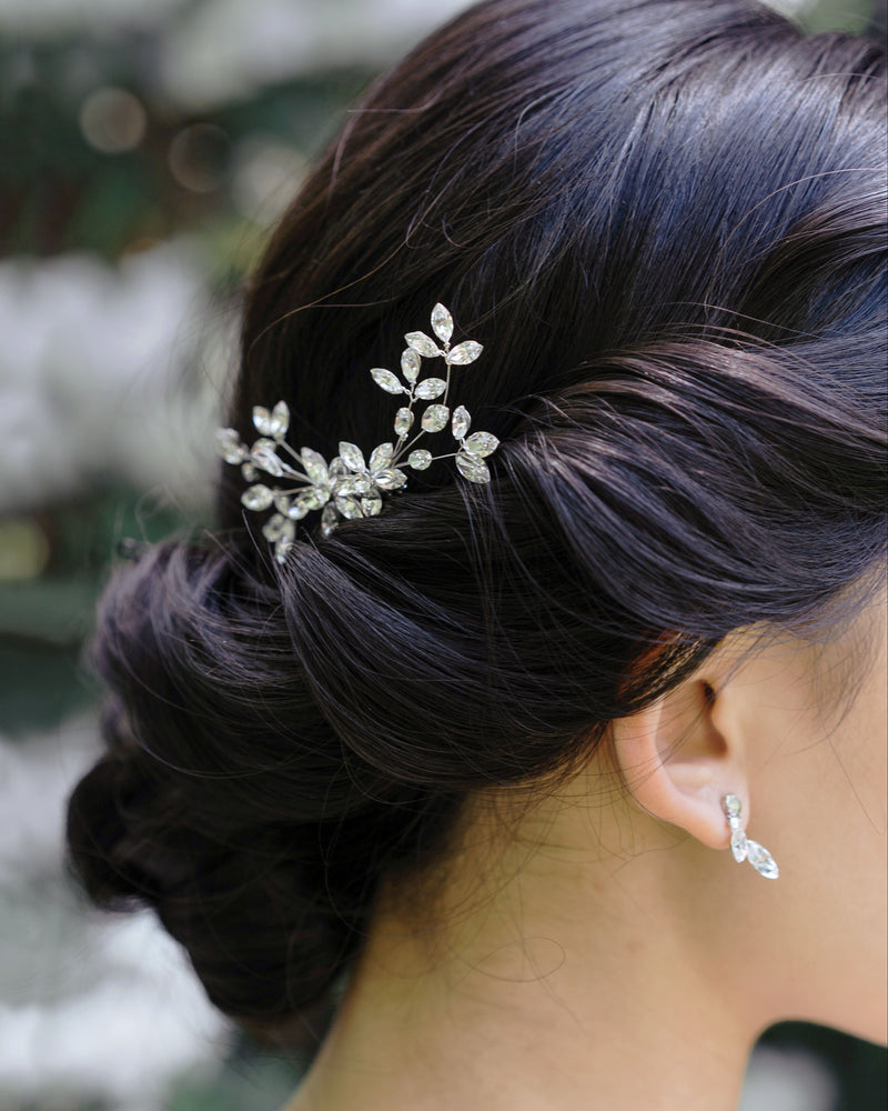 A close model view of the Crystal Blossoms Petite Comb styled to the side in a low bridal updo.