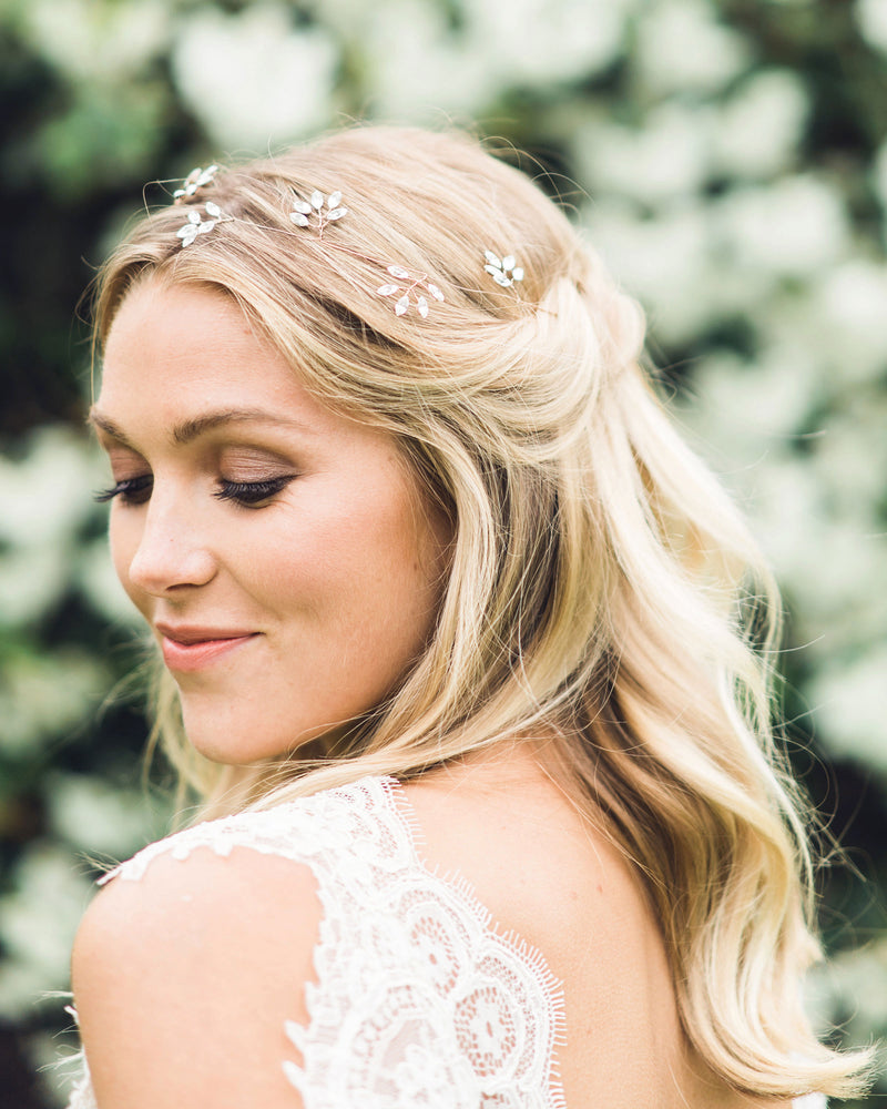 A blonde model wears the Crystal Leaf Hair Vine in her hair, which is styled in a half up bridal updo.