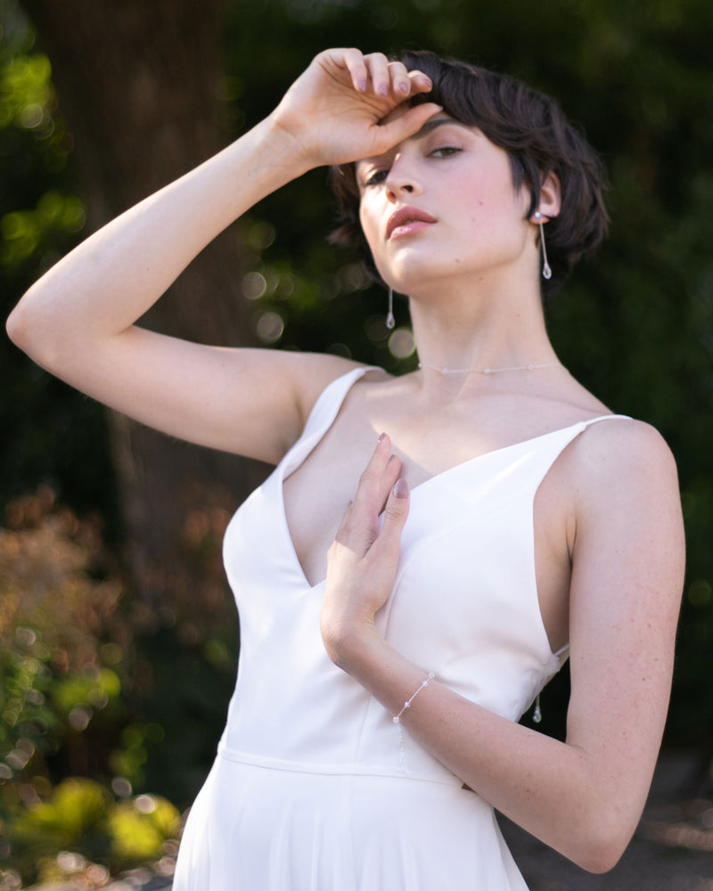 A model wears the Dainty Crystal Bracelet with the Dewdrop Long Earrings and Crystal Back Drape in silver.