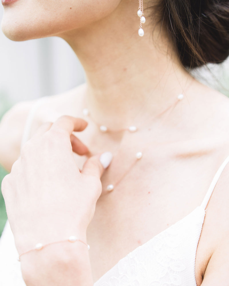 A close model view of a delicate layered pearl bridal necklace and matching dainty pearl bracelet.