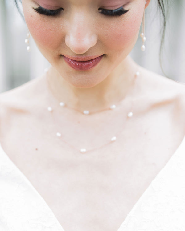 A close-up of a model wearing our Dainty Pearl Layered Necklace in rose gold with matching Dainty Pearl Trio Earrings.