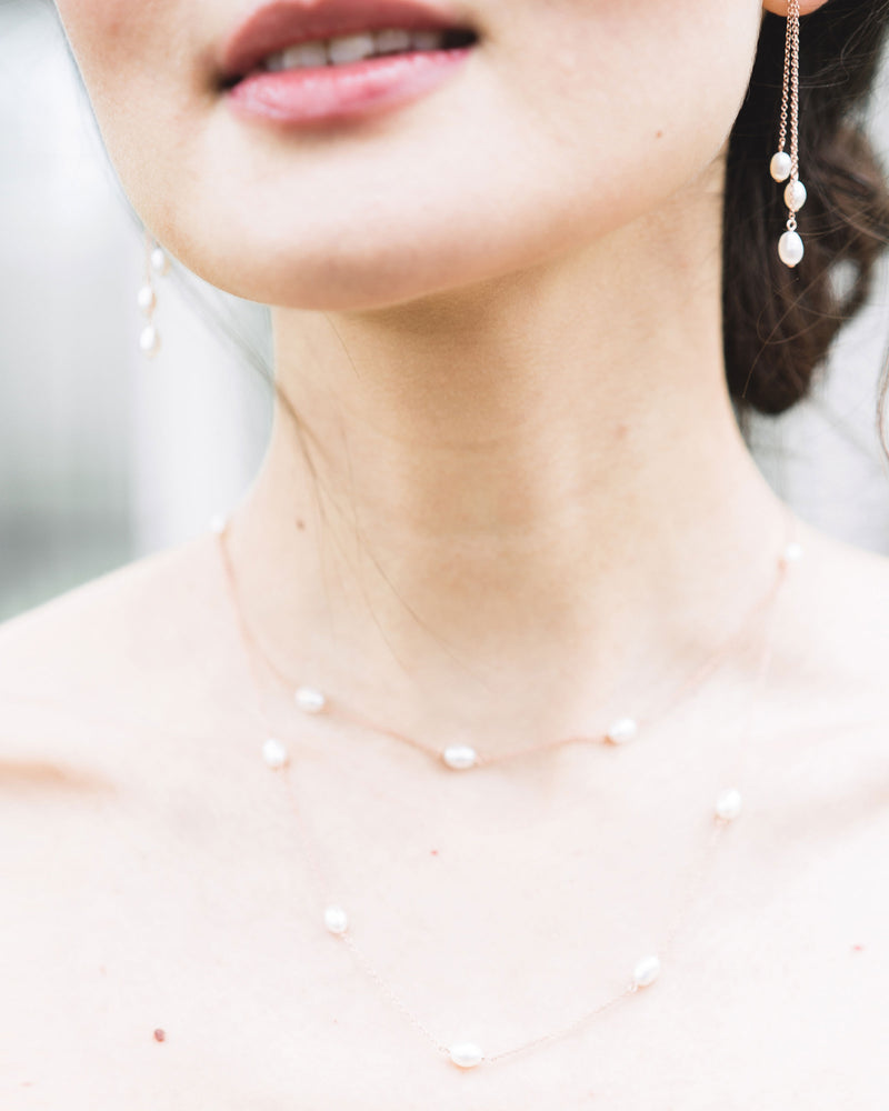 A close-up view of the dainty layered pearl necklace, paired with the dainty pearl trio earrings.