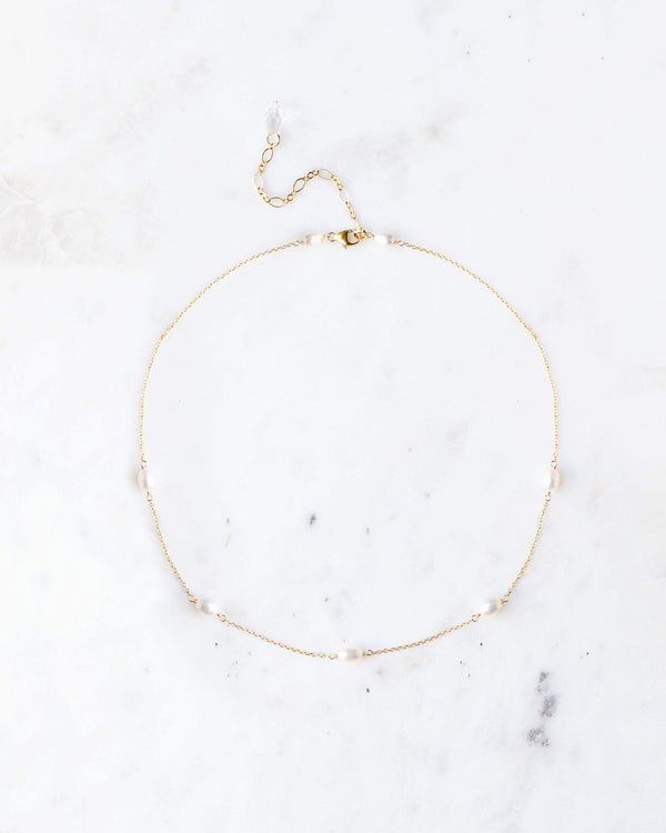 Flatlay of the Dainty Pearl Necklace in gold, with five scattered freshwater pearls on a delicate chain.