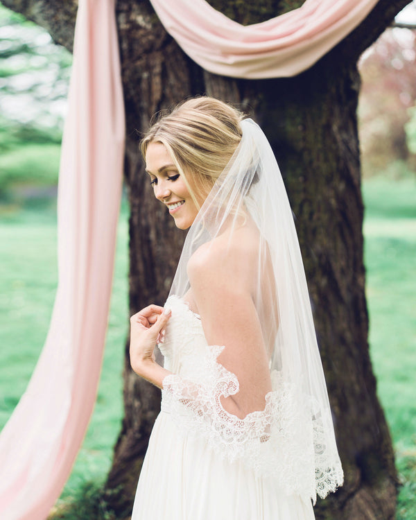 A model is wearing a playful waist veil with a intricate Chantilly lace edge. 