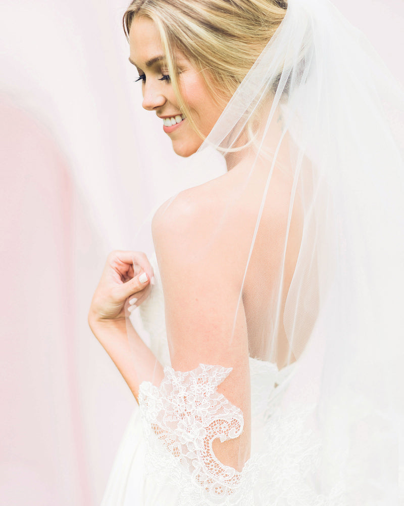 Model wearing playful wedding veil with intricate Chantilly lace 
