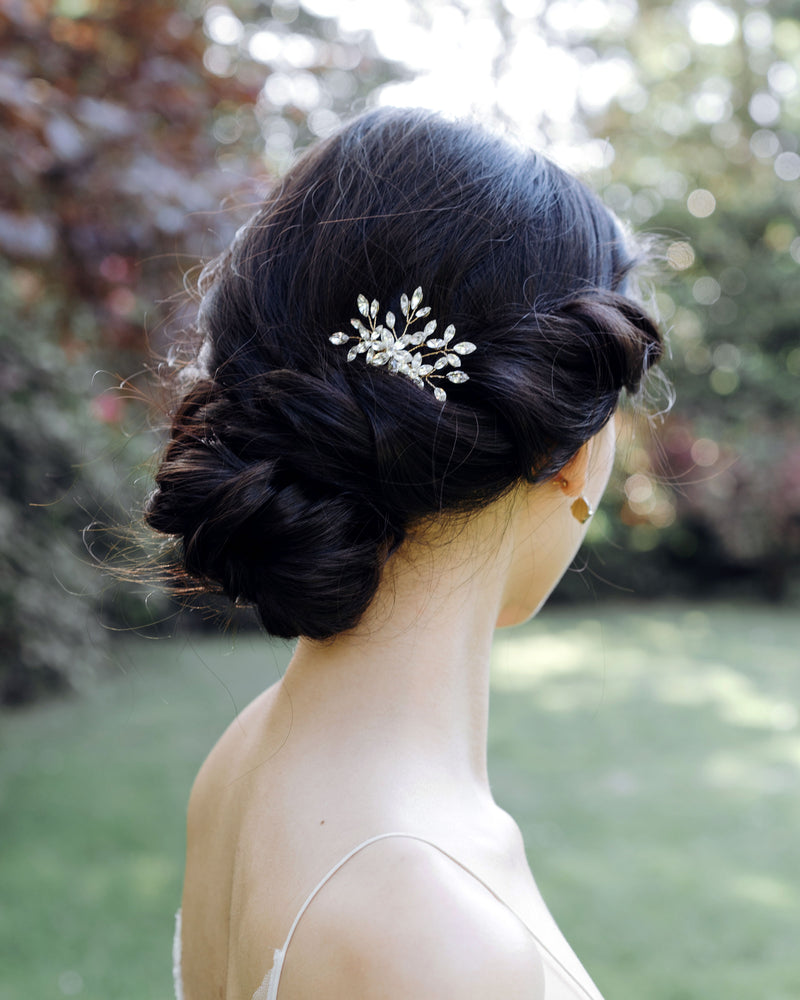 A model is wearing the Delicate Comb in silver and all-crystal, styled into her low bridal updo.