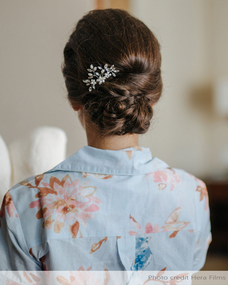 A getting ready photo of a bride with her hair styled in a low updo. She wears the Delicate Comb in silver with pearls and crystals.