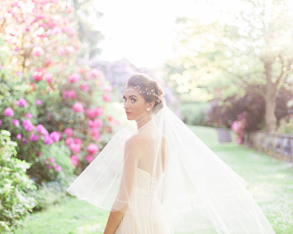 A model poses at golden hour at Aberthau Mansion. The two-layer Delphine Veil is styled with its blusher to the back and the tulle floats softly as she turns.