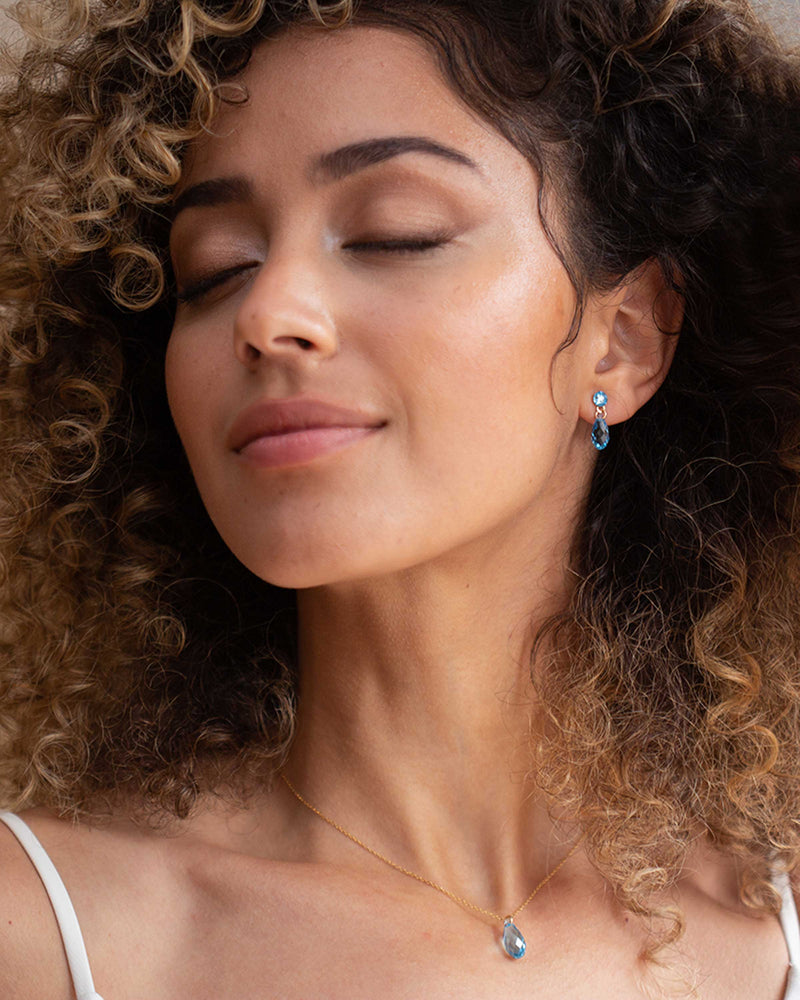 A model wears the Dewdrop Crystal Jewelry Set in gold with aquamarine crystals.