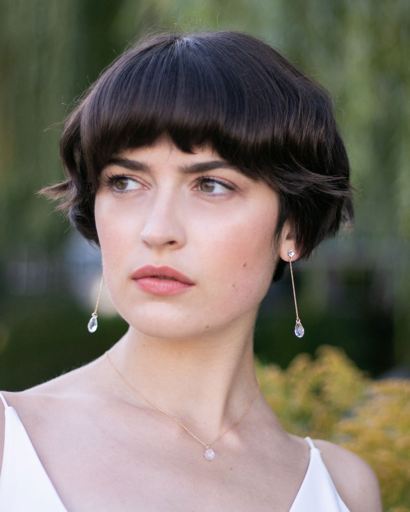 A model wears the Dewdrop Luxe Long Earrings in gold.
