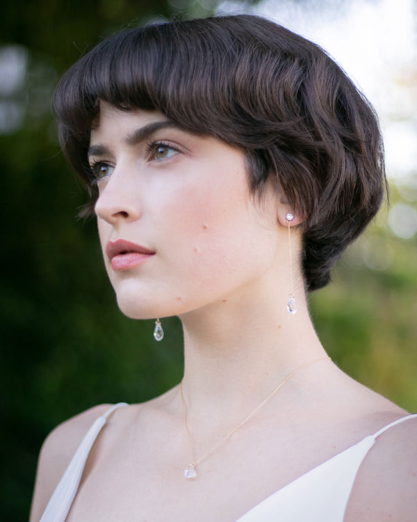A bride models the Dewdrop Crystal Necklace in gold alongside the Dewdrop Luxe Long Earrings.