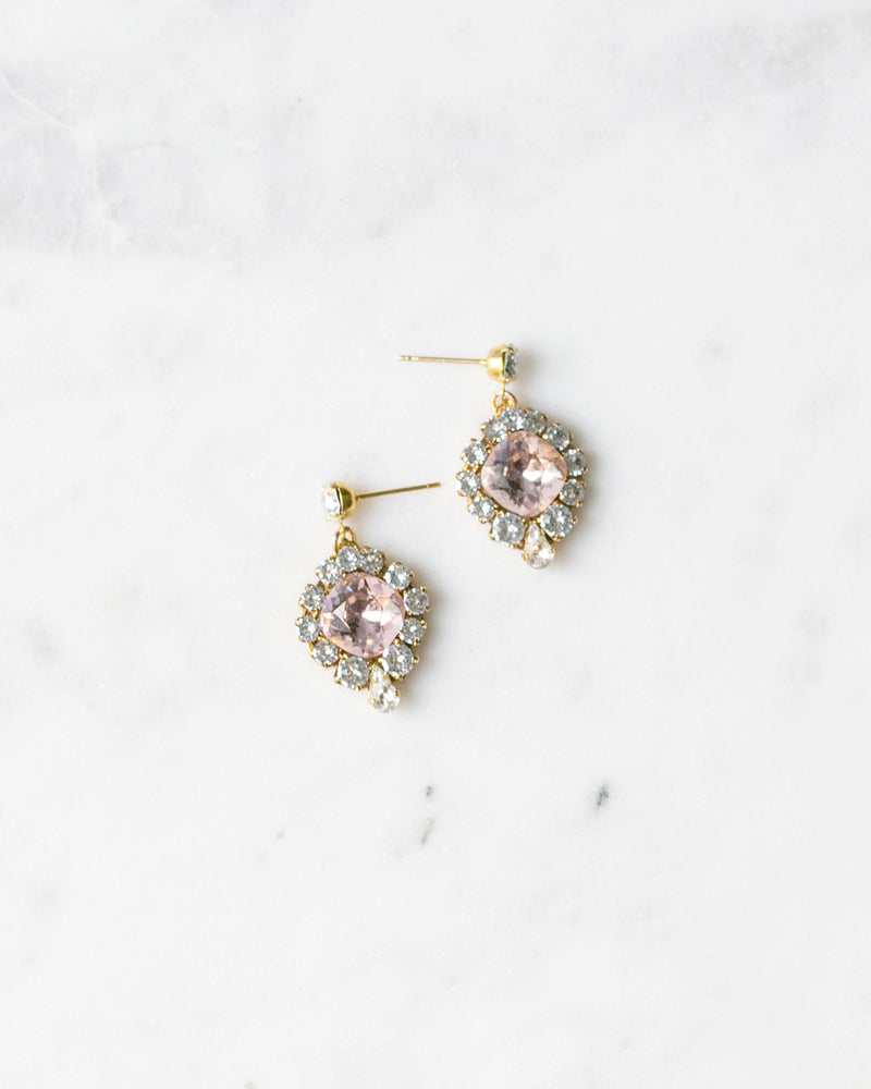 Flatlay of the Enchanted Crystal Drop Earrings in gold with blush crystal centers.