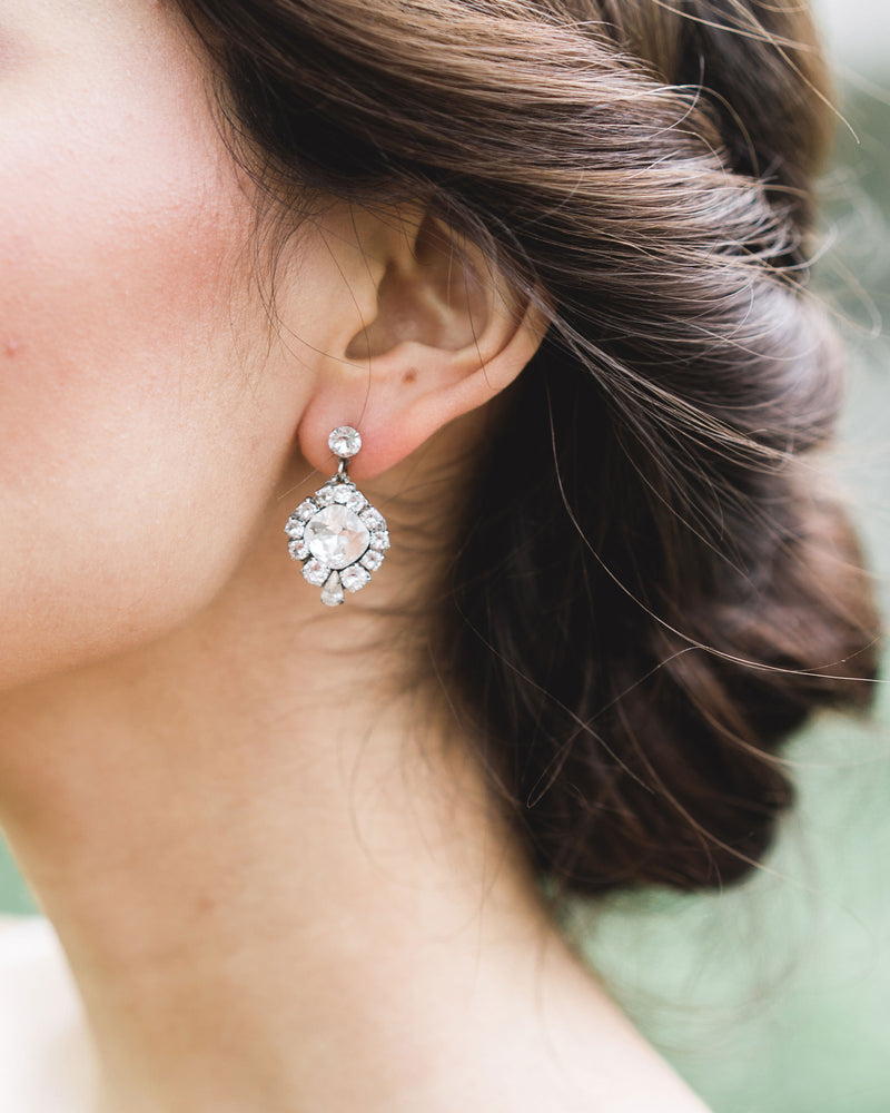 A close model view of a bride wearing the Enchanted Crystal Drop Earrings in silver with crystal centers. 