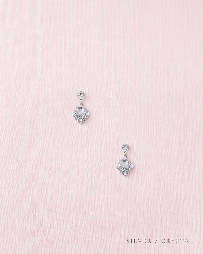 A flatlay view of the Celestial Crystal Drop Bridal Earrings in silver with all crystal.