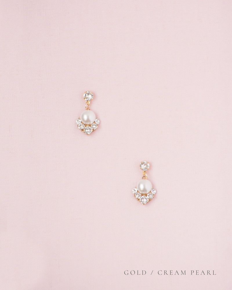 A flatlay view of the Celestial Pearl Drop Earrings in gold with cream pearls.
