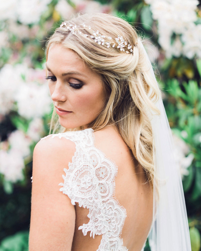 A bride wears her hair with soft bridal waves, with the sides pinned up. The Everthine Crystal Hair Vine is styled to the front, with a veil in the back.