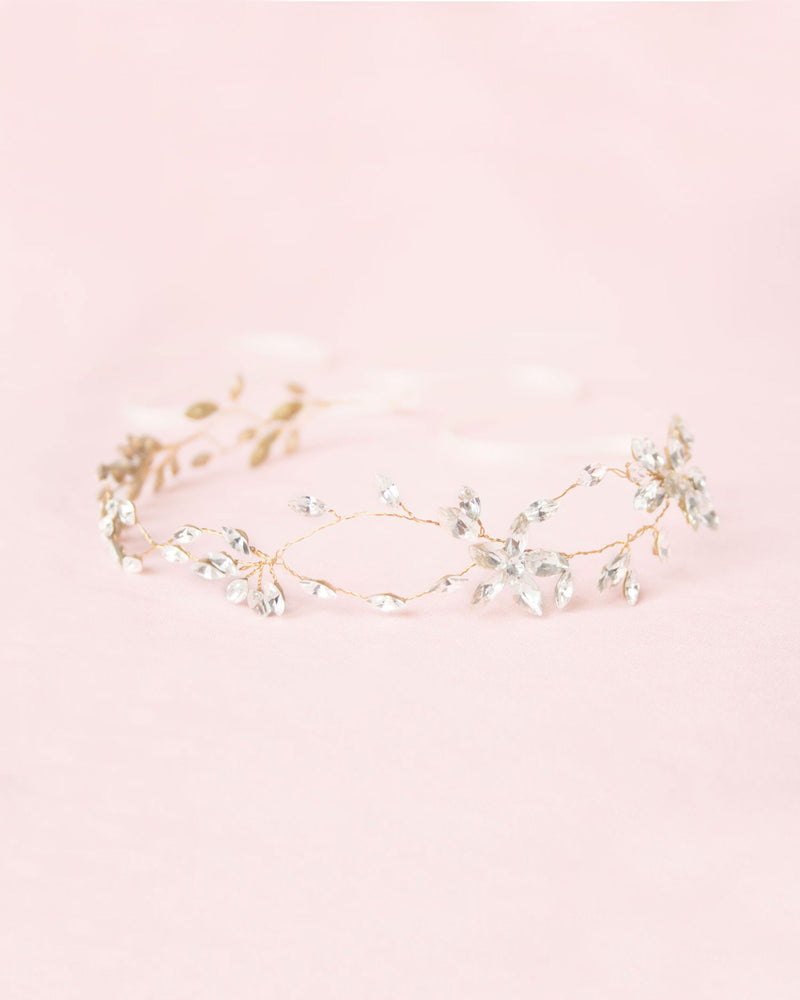Flatlay on a pink background of the Everthine Hair Vine; clusters of crystal leaves in an intricate asymmetric design.