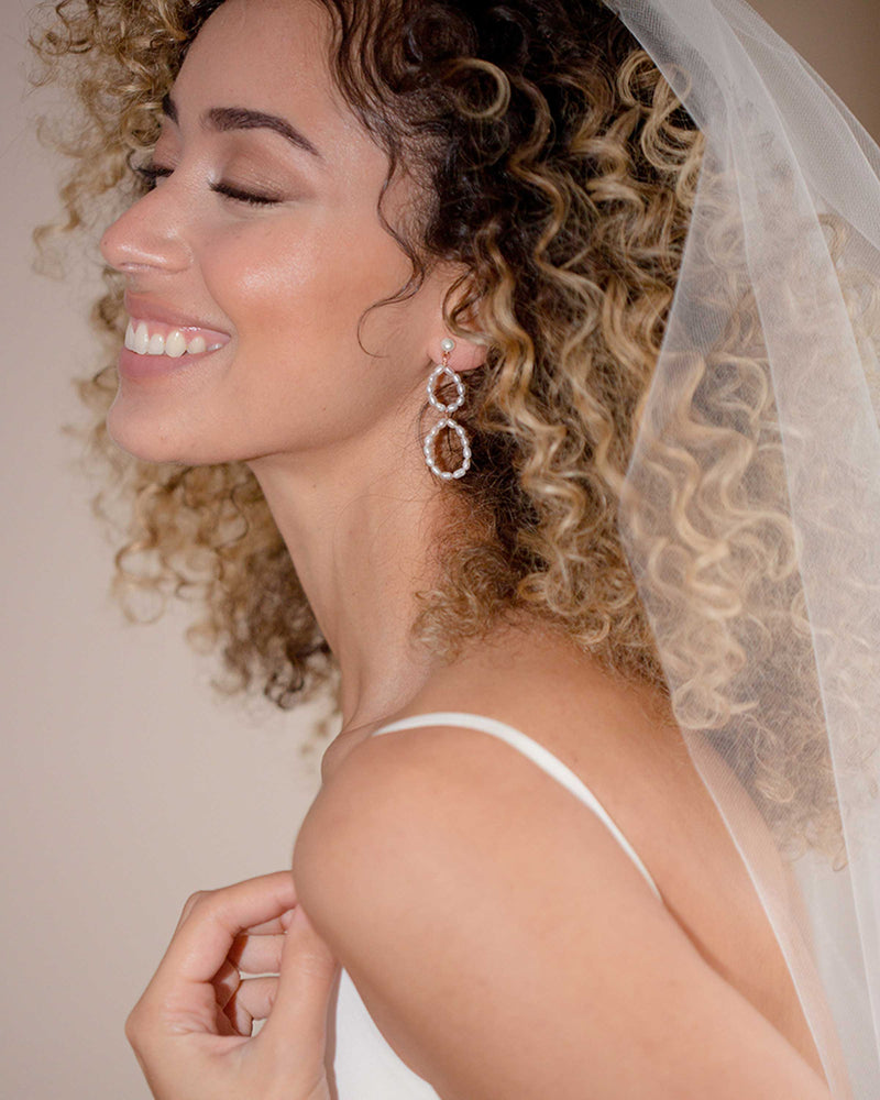 A bride wears the Evi Pearl Earrings with a veil.