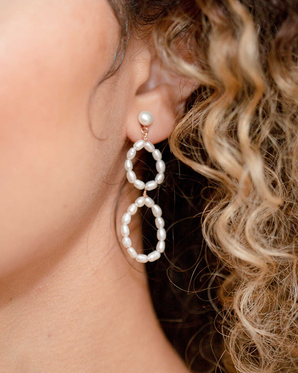 A close model view of the Evi Pearl Earrings in rose gold.