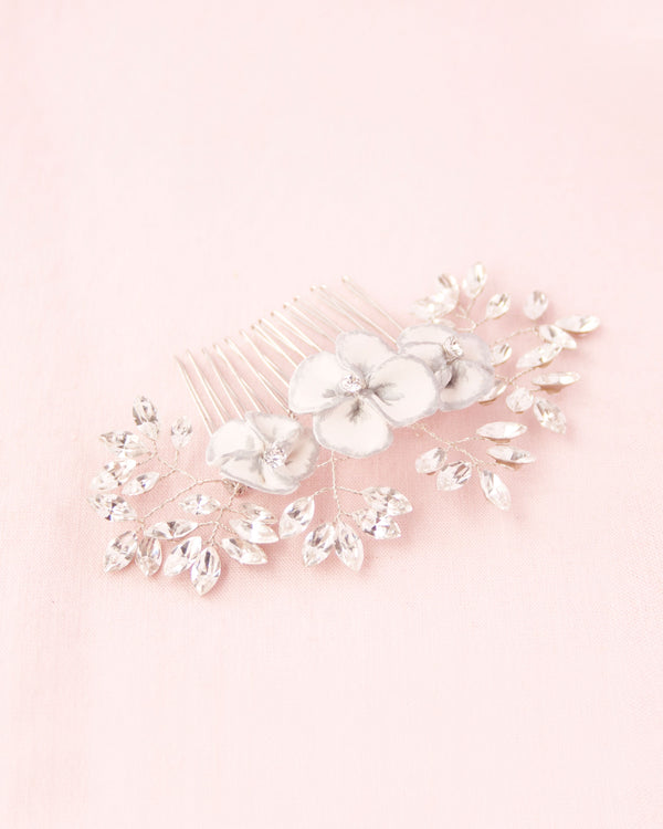 Flatlay on pink background of delicate comb of hand-painted flowers, freshwater pearls and scattered crystals.