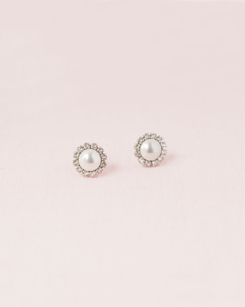 Flatlay on pink background of the Halo Pearl Stud Bridal Earrings in silver with white pearls.