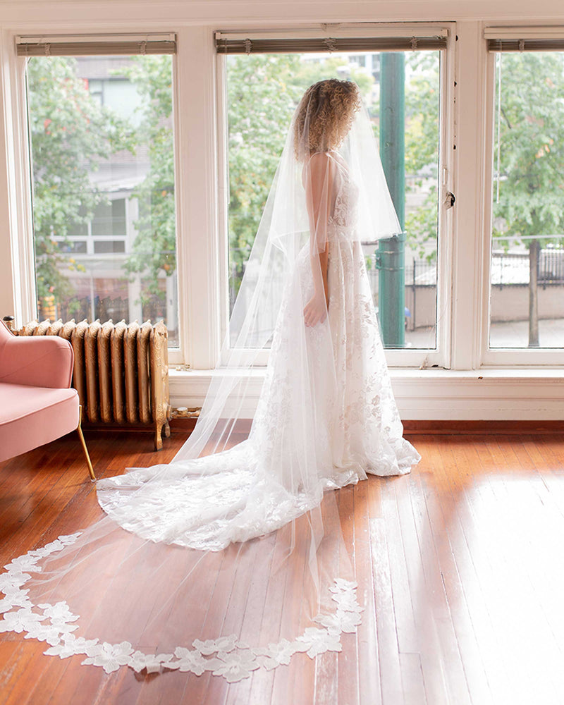 A bride wears the Hibiscus Circular Veil in extended chapel length with blusher forward.