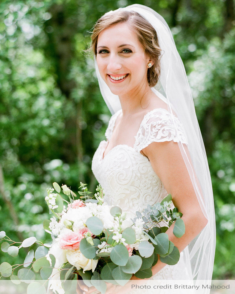 A real bride wears the Leila Veil; a fingertip length veil with delicate ribbon trim.