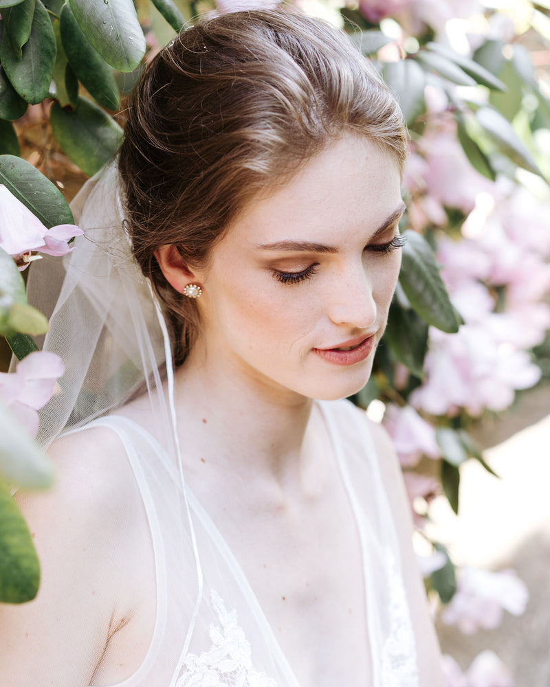 A bride wears a veil with a delicate ribbon trim.