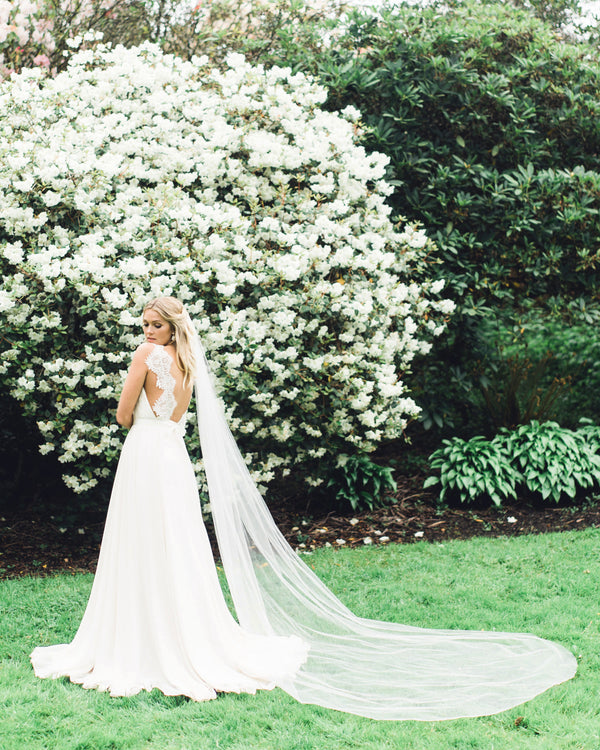 A bride wears a cathedral single layer illusion tulle veil with a delicate hand cut edge.