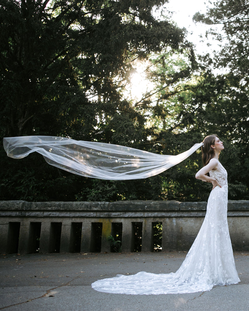 A bride wears a veil that floats in the air behind her. The veil is long, with no trim.
