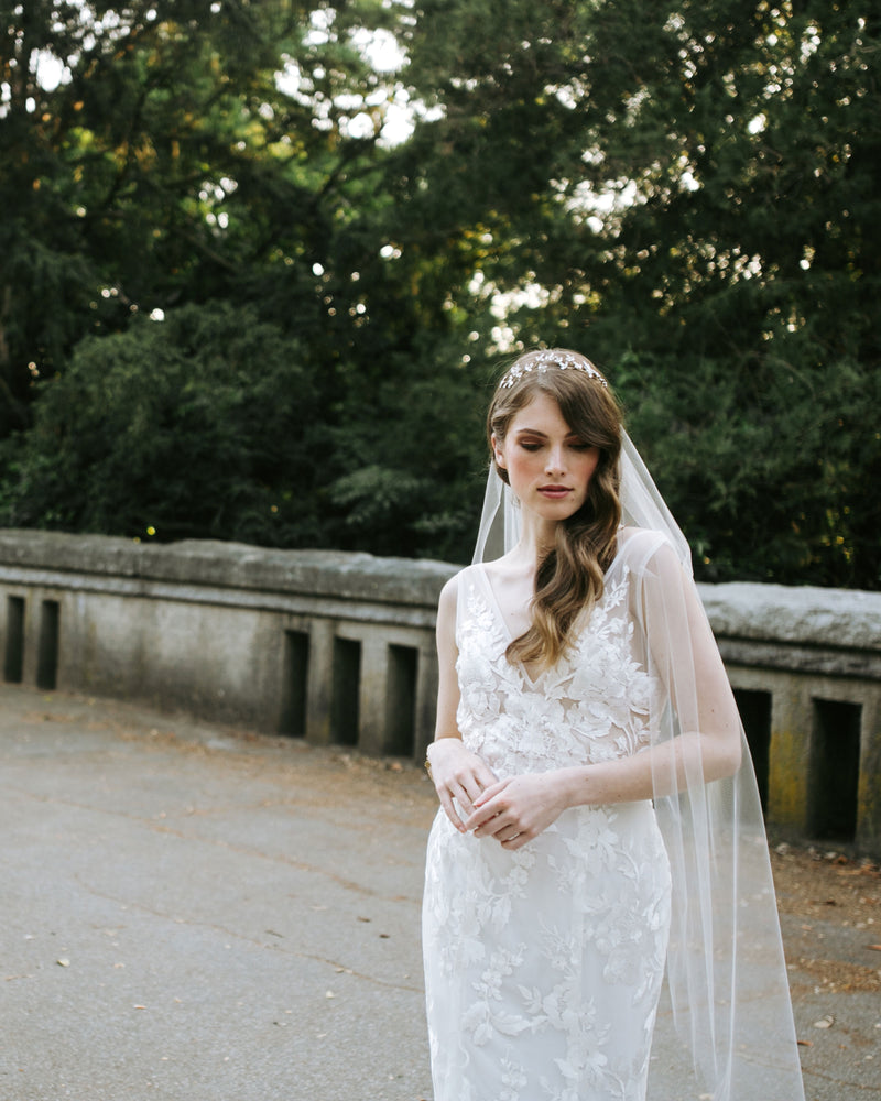 A bride wears the Lily Fingertip Veil with a V-neckline dress and crystal hair vine.