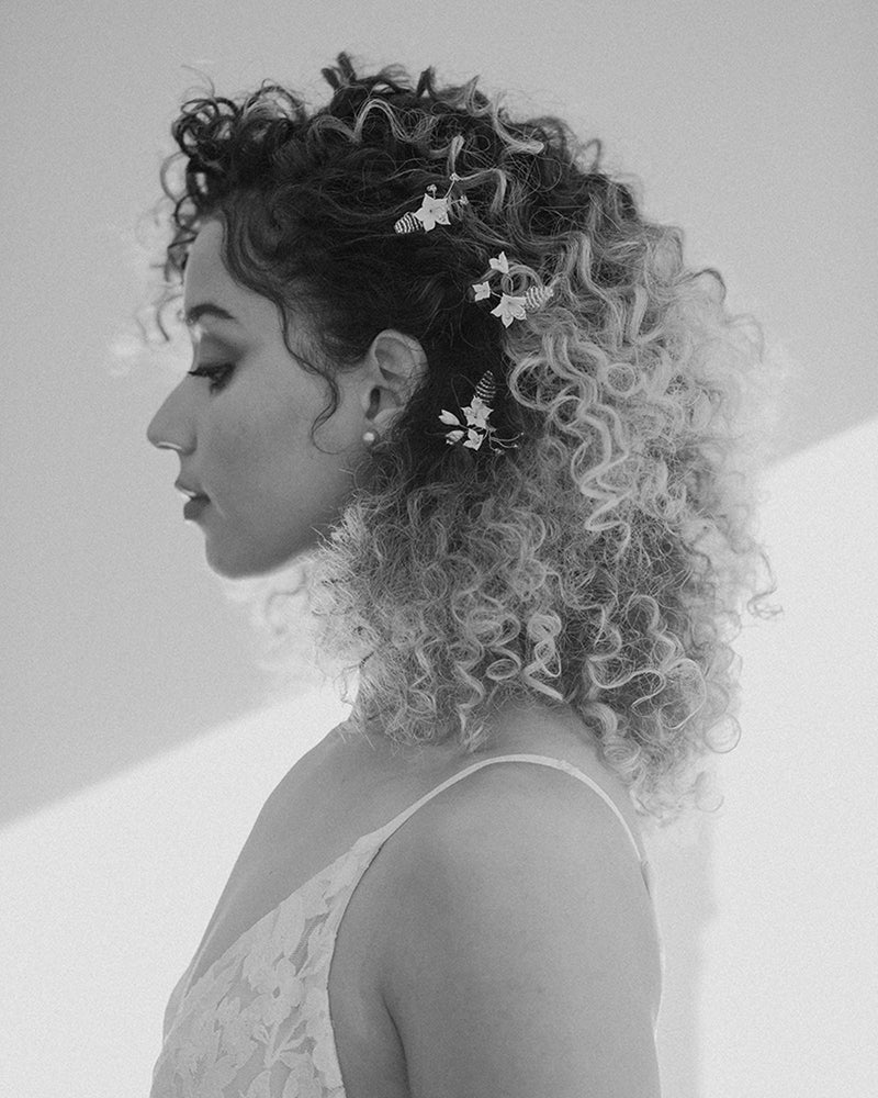 A black and white artistic view of a model wearing our Lily Floral Hair Pins and Classic Pearl Stud Earrings.
