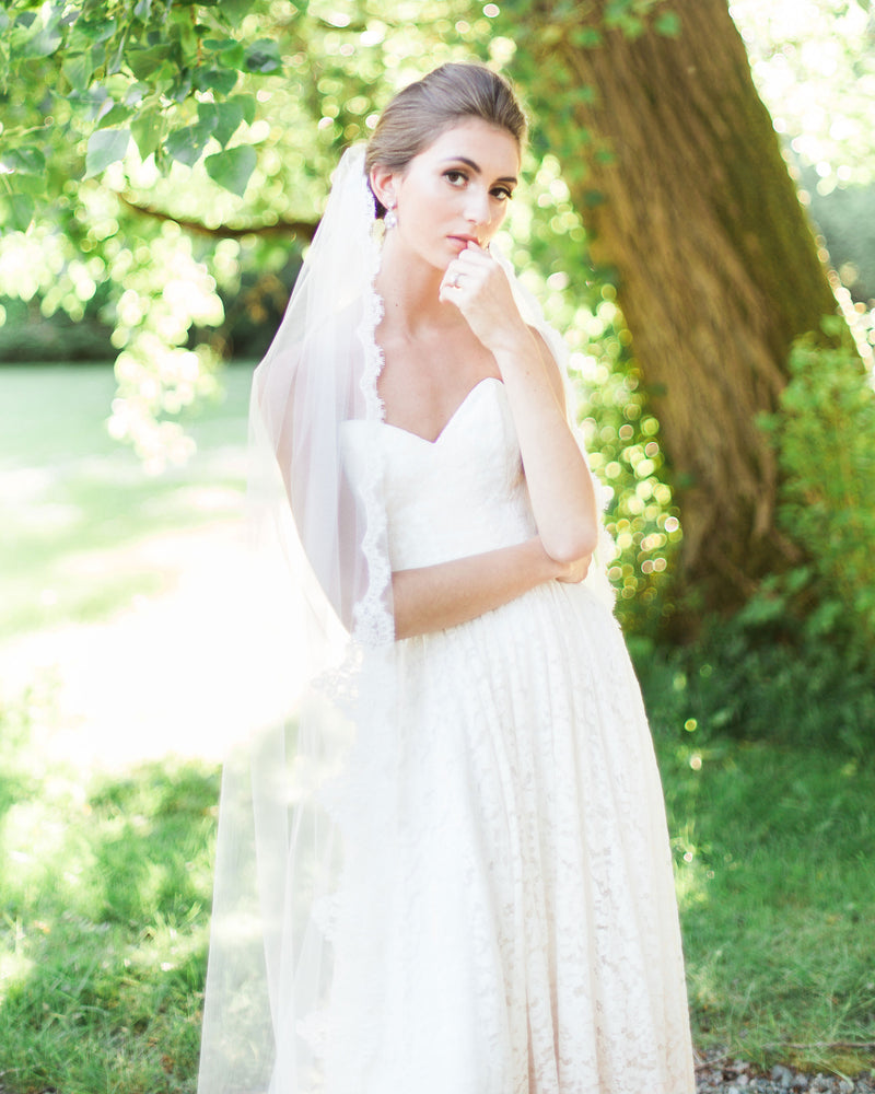 A bride wears the Magnolia Alencon Lace Veil in chapel length.