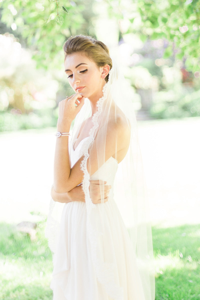 A bride wears the Magnolia Lace Veil in fingertip length.