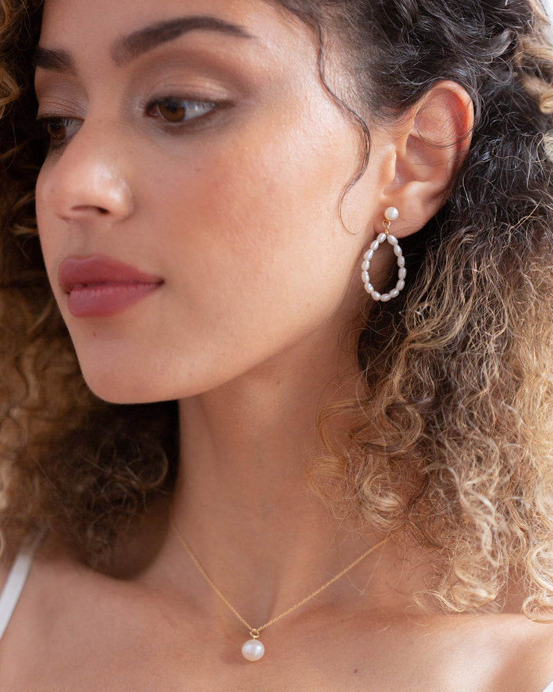 Models wears the Mira statement pearl earrings in gold with the Moondrop round pearl necklace.