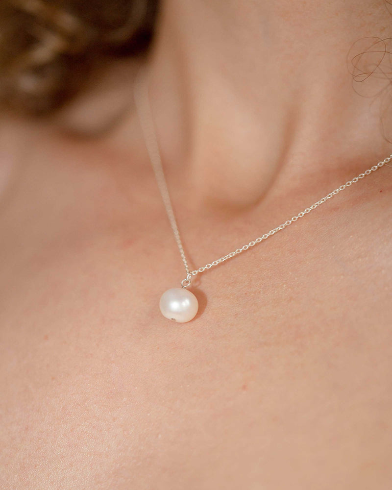 A close-up on model view of the Moondrop Pearl Necklace in silver.