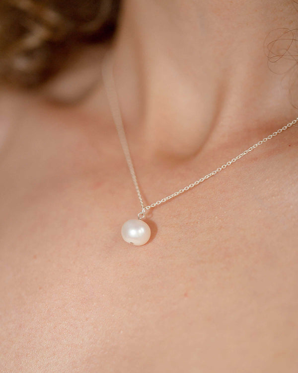 A close-up on model view of the Moondrop Pearl Necklace in silver.