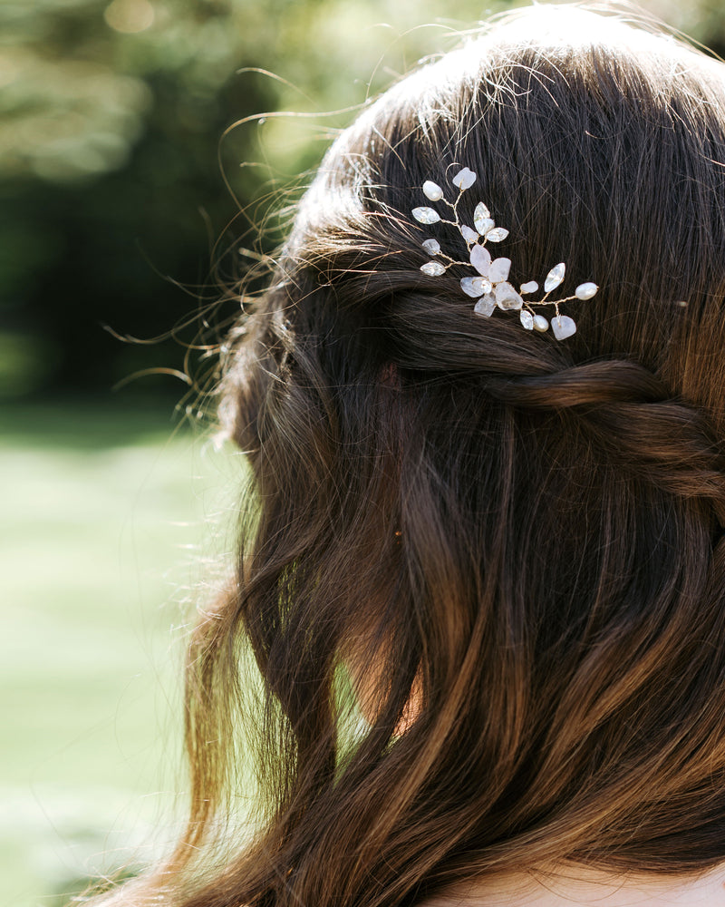 A bride with hair down and braids wears the Moonflower Comb in gold, with rose quartz gemstones, pearls, and crystals.