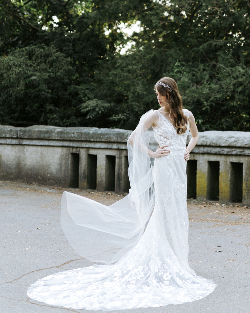 A bride wears the Aster Cape Veil, paired with the Moonflower Bridal Hair Vine.