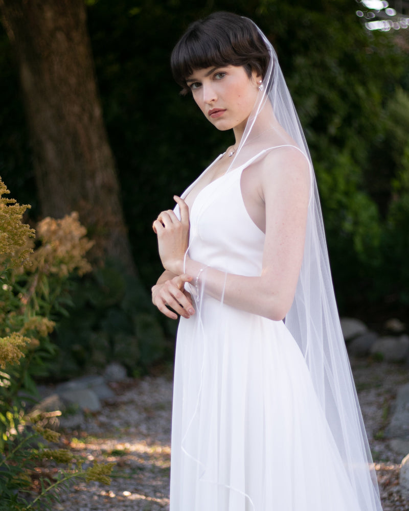 A bride wears the Primrose Ribbon Veil in cathedral length.