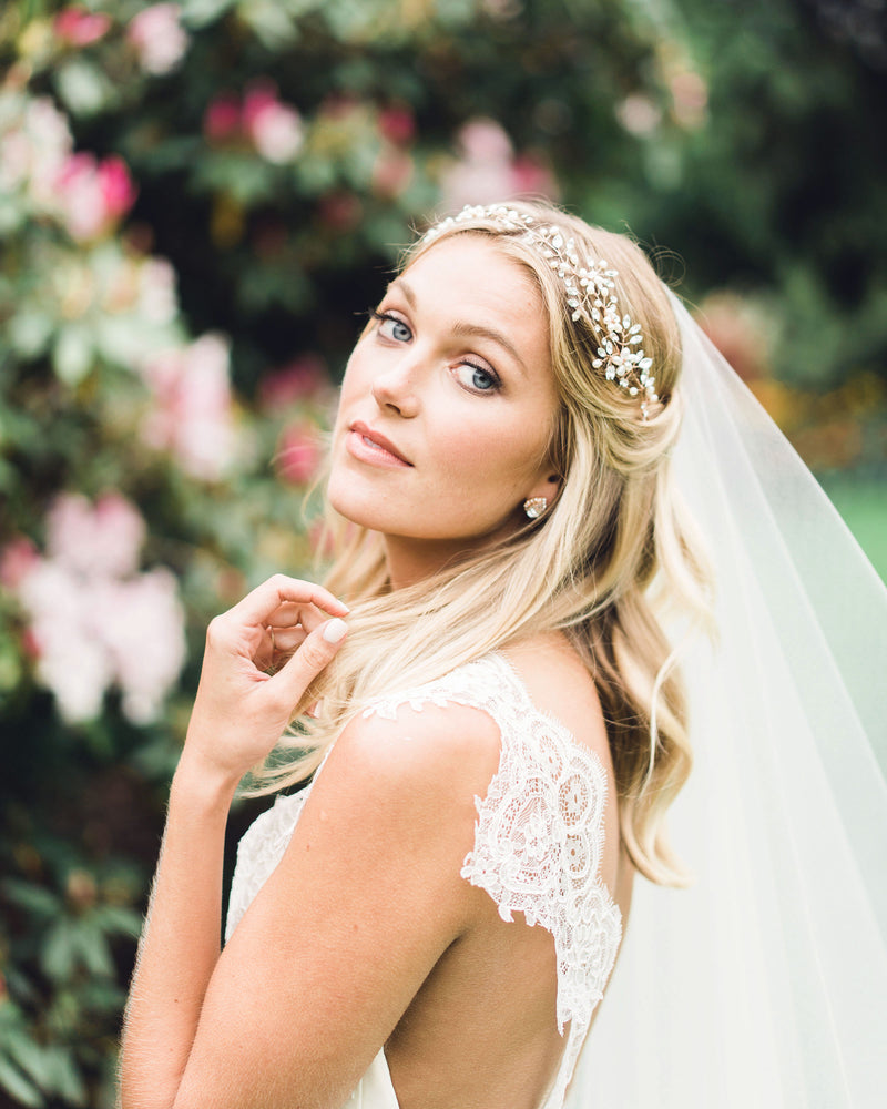 A model wears a dramatic hair vine for brides with pearls and scattered crystals in rose gold.