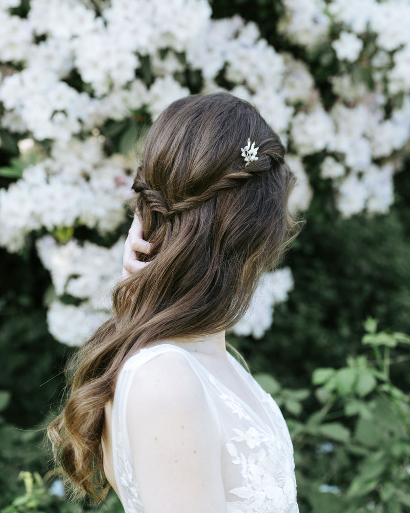 A bride wears a single Sea Mist Hair Pin in her hair, styled in soft waves with twisted pieces pinned back.