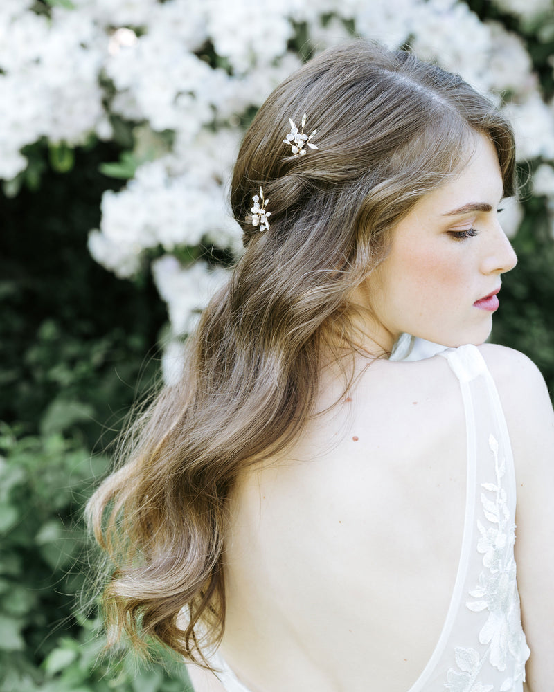 A bride wears two Sea Mist Hair Pins in her hair, styled in soft waves with pieces pinned back.