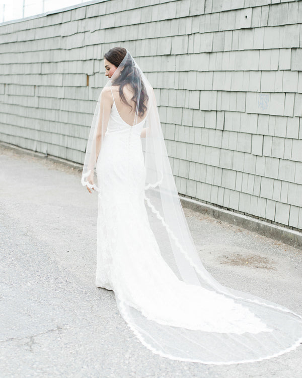 A bride wears the Senna Lace Chapel Veil with a lace scallop edge and no gathers.