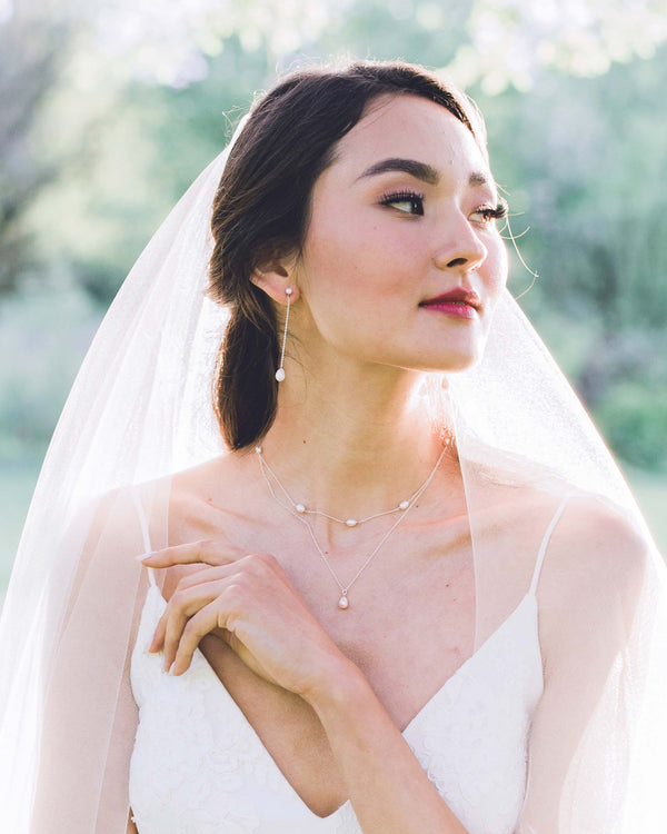 Bride wears a layered pearl necklace in silver by Atelier Elise with matching long pearl drop earrings.